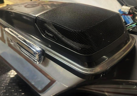 Black mesh speaker grille installed on a dark motorcycle saddlebag