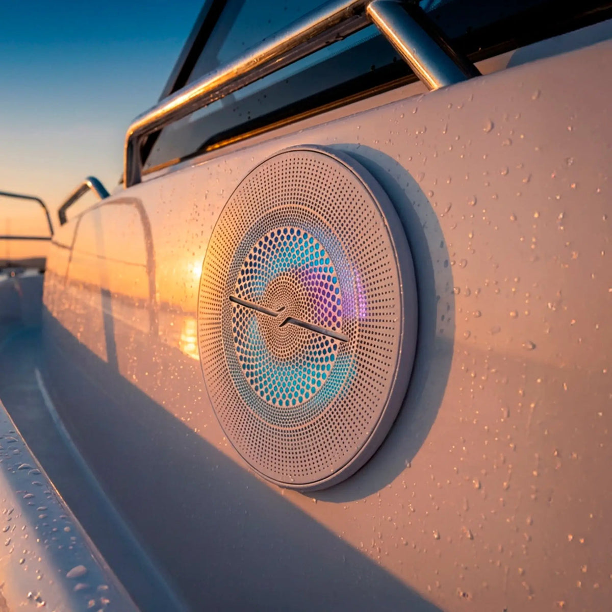 White DS18 mesh-grille speaker with multicolor illumination installed in a boat panel at sunset