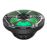 Low front view of a black speaker showing its silver honeycomb grille, green lighting and open basket