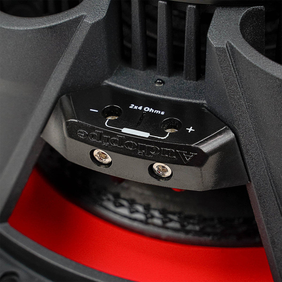 Close-up of a two-terminal subwoofer block marked 2x4 ohms, with positive and negative markings