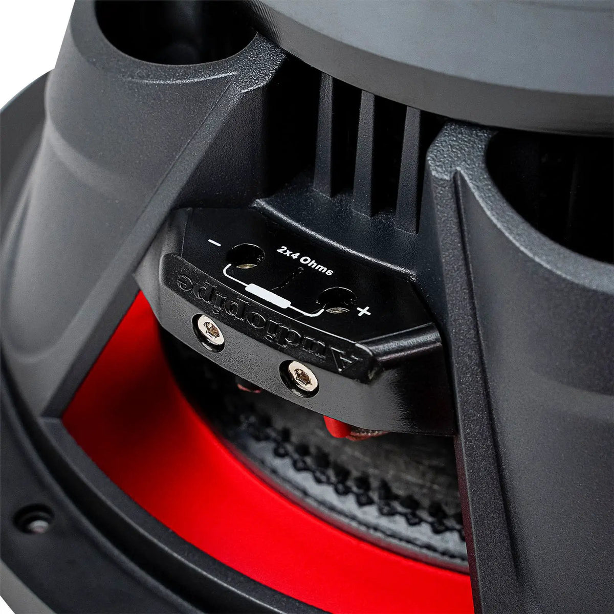 Close-up of an Audiopipe subwoofer terminal block marked 2x4 ohms, with positive and negative connections