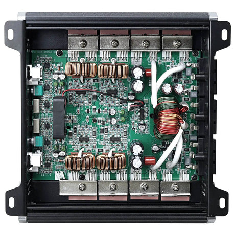 Open amplifier chassis showing a green circuit board, copper coils and internal wiring