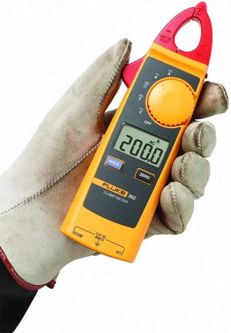 Gloved hand holding a yellow Fluke 362 clamp meter with red jaws and a display reading 200.0