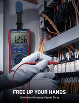 DM6000AR multimeter hanging by a magnetic strap while gloved hands use test probes at an electrical panel