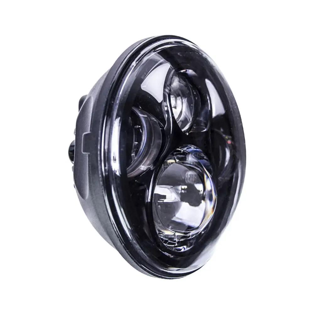 Angled view of a round black motorcycle headlight with projector lenses and partial halo