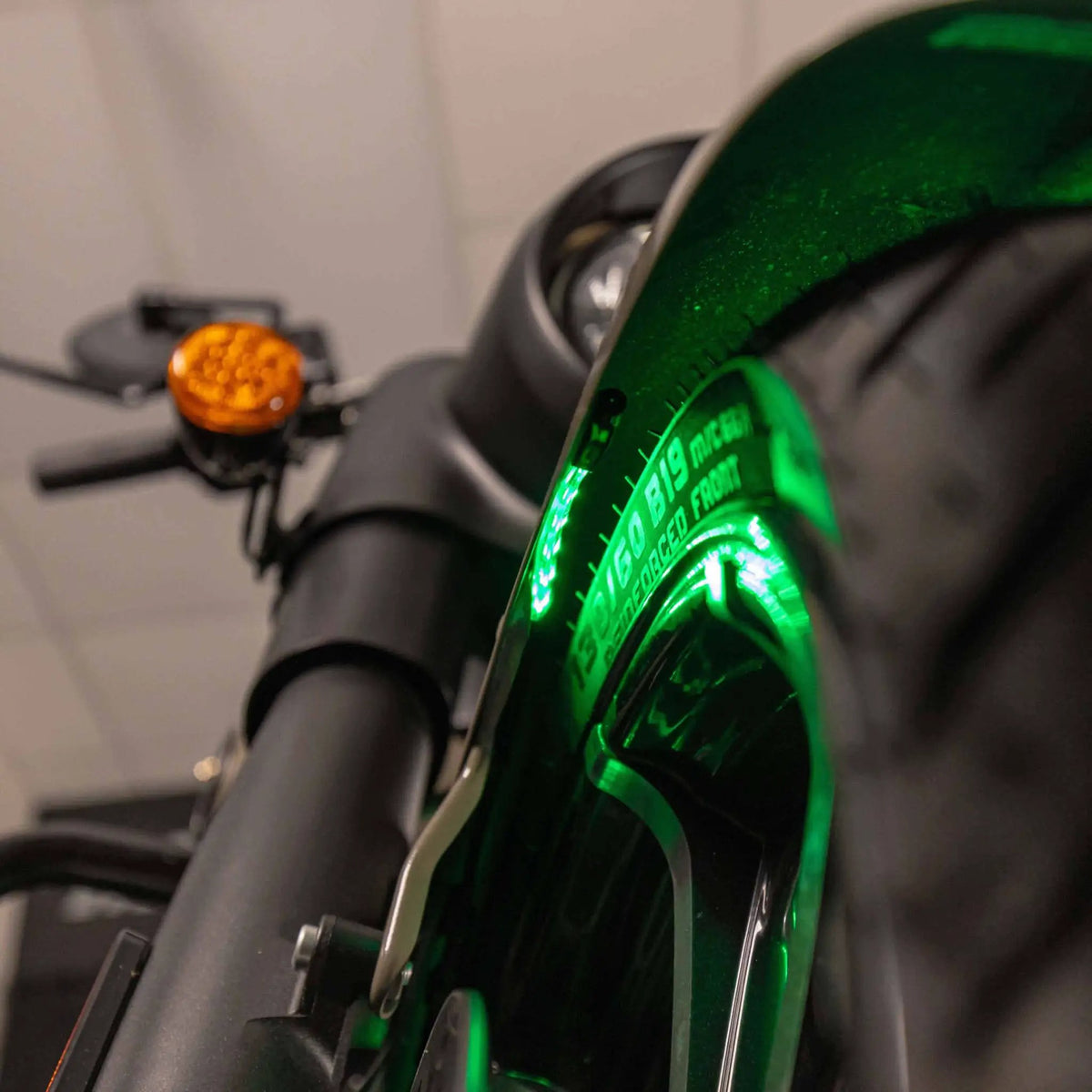 Close-up of green accent lighting beneath a motorcycle fender