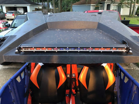 Slim LED light bar mounted above the orange and black seats of an off-road vehicle