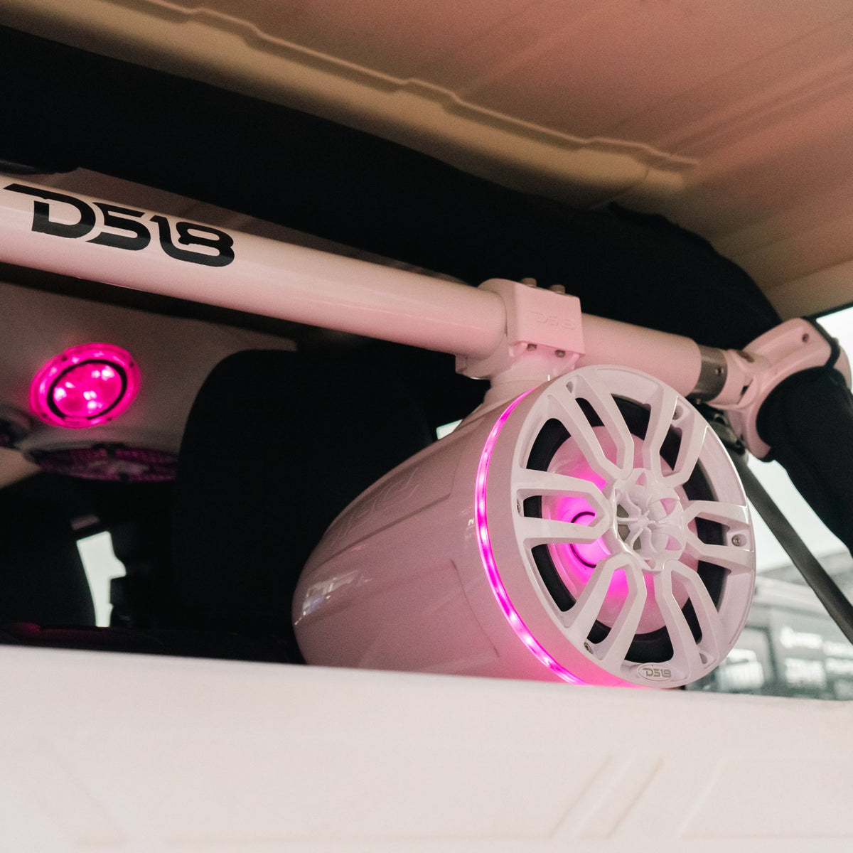 White DS18 tower speaker mounted on an overhead bar with pink illumination