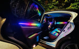 Car interior with rainbow-colored ambient lighting along the open doors and dashboard