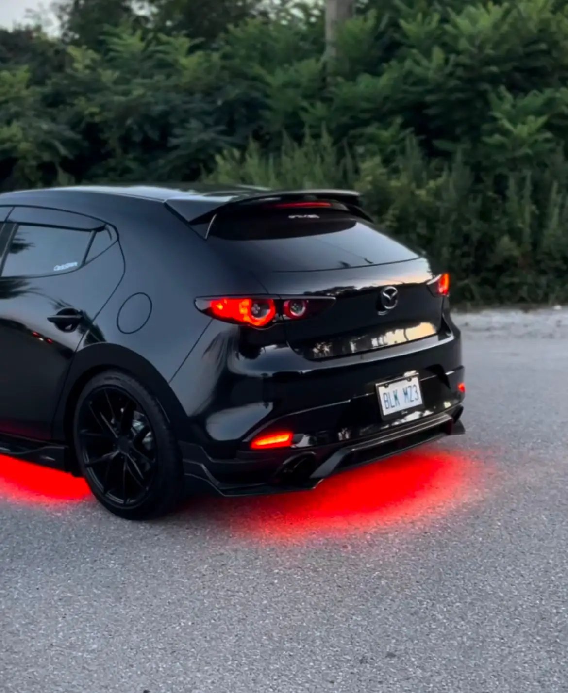 Black hatchback with red underglow lighting beneath its rear bumper