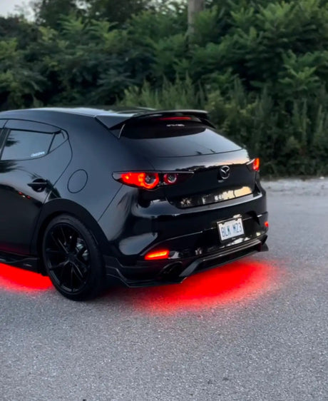 Black hatchback with red underglow lighting beneath its rear bumper