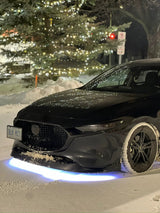 Black car in snow with blue-white underglow beneath the front bumper