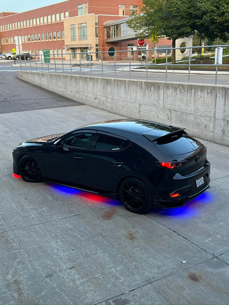 Black hatchback with red and blue underglow lighting along the pavement