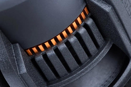 Close-up of a black subwoofer basket with narrow vent slots and orange fins