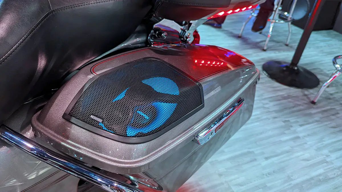 Motorcycle saddlebag with a blue-lit speaker beneath a black mesh grille
