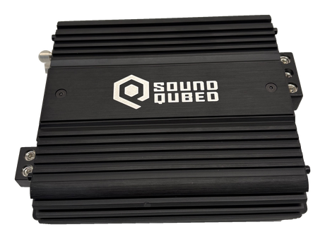 Angled view of a black SoundQubed amplifier with a finned housing and logo on top