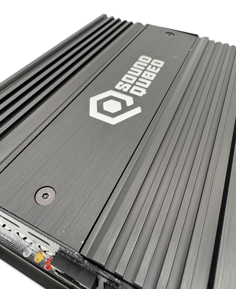 Close-up of a SoundQubed amplifier top showing its logo, recessed screws and parallel cooling fins