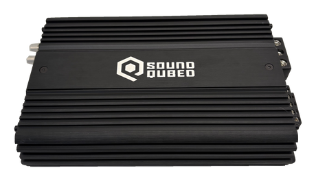 Top view of a black SoundQubed amplifier with a large white logo between rows of cooling fins