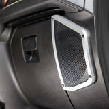 Rectangular speaker grille with silver trim installed in black vehicle interior paneling