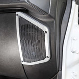 Close-up of a silver-trimmed mesh speaker grille in a vehicle panel beside the open door