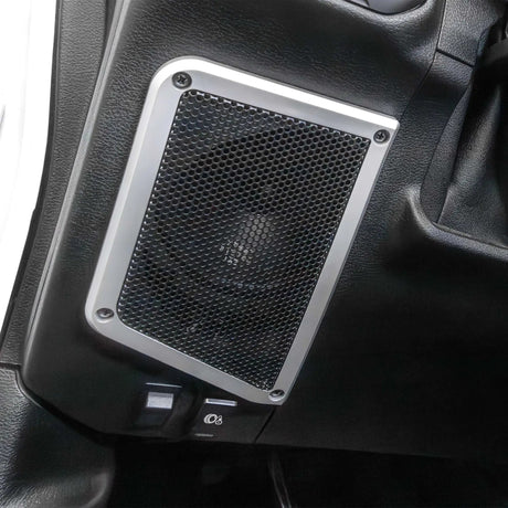 Installed subwoofer enclosure with a round mesh grille and silver mounting frame